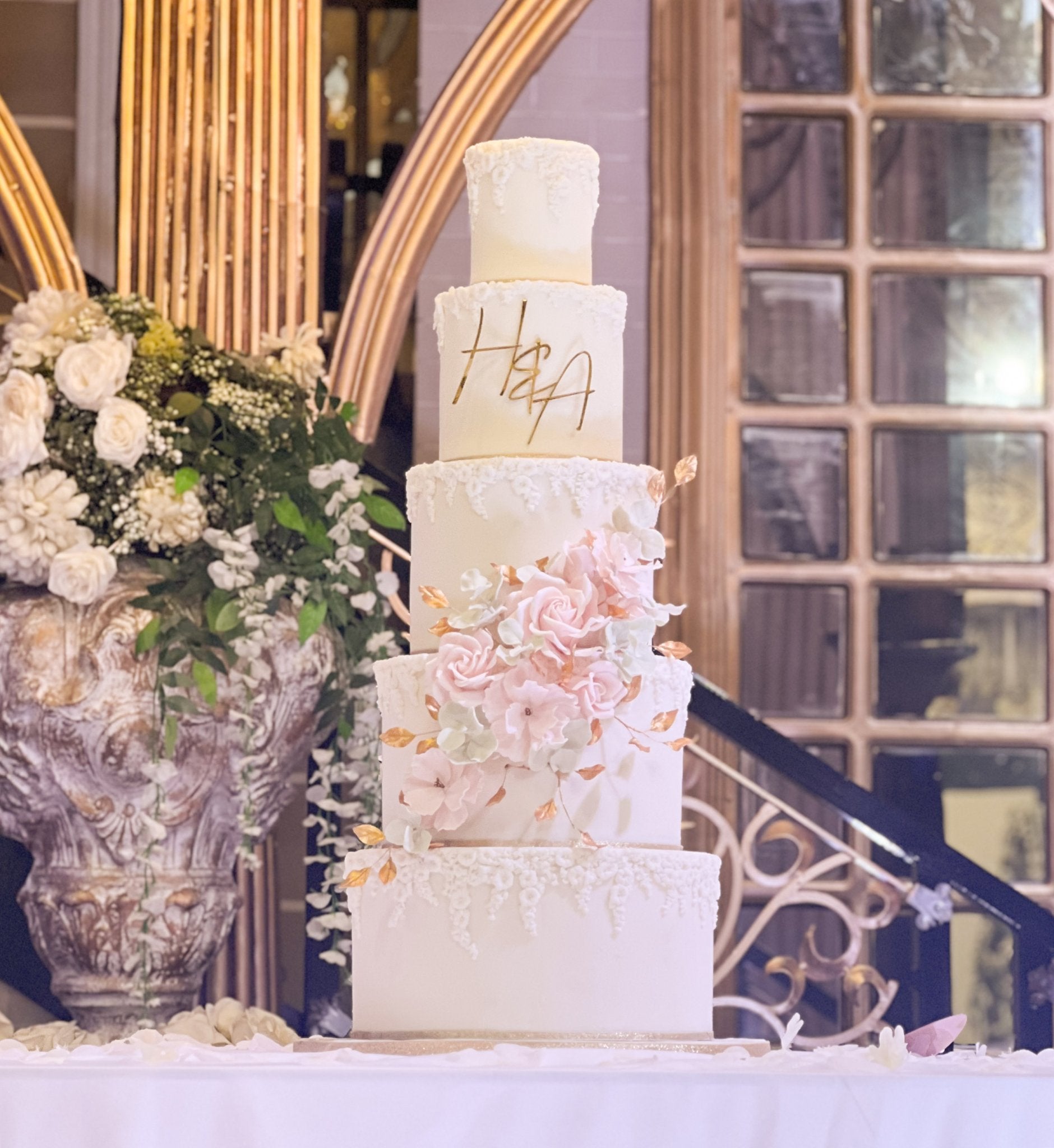 Pink and gold floral five-tier wedding cake with elegant decorations.
