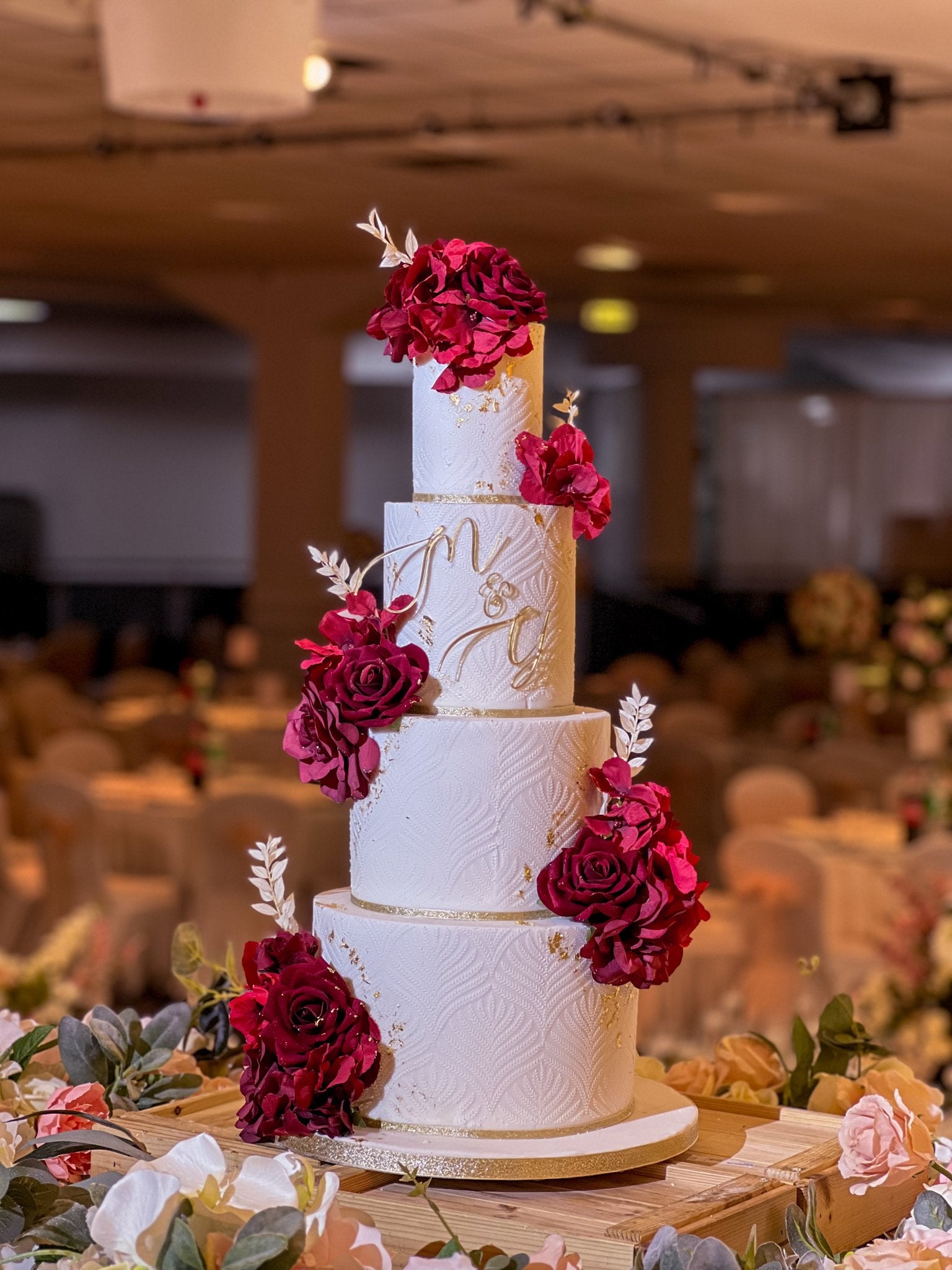 Four-tier wedding cake with roses and gold accents